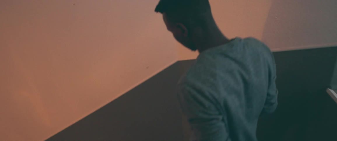 High angle shot of a man in a grey sweatshirt walking down the stairs of a building
