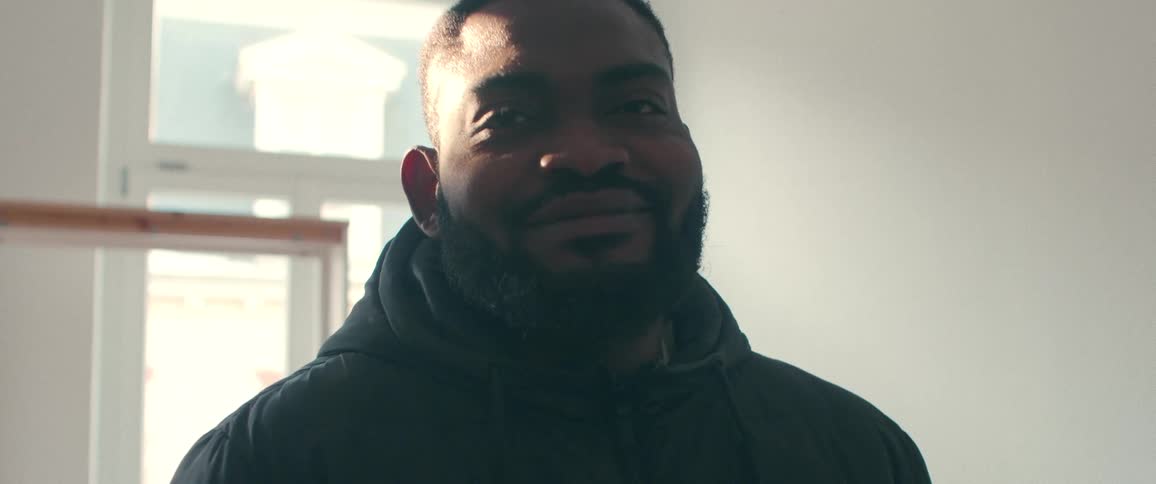 Close-up slow-motion portrait of a kind-faced Black man with a beard smiling gently