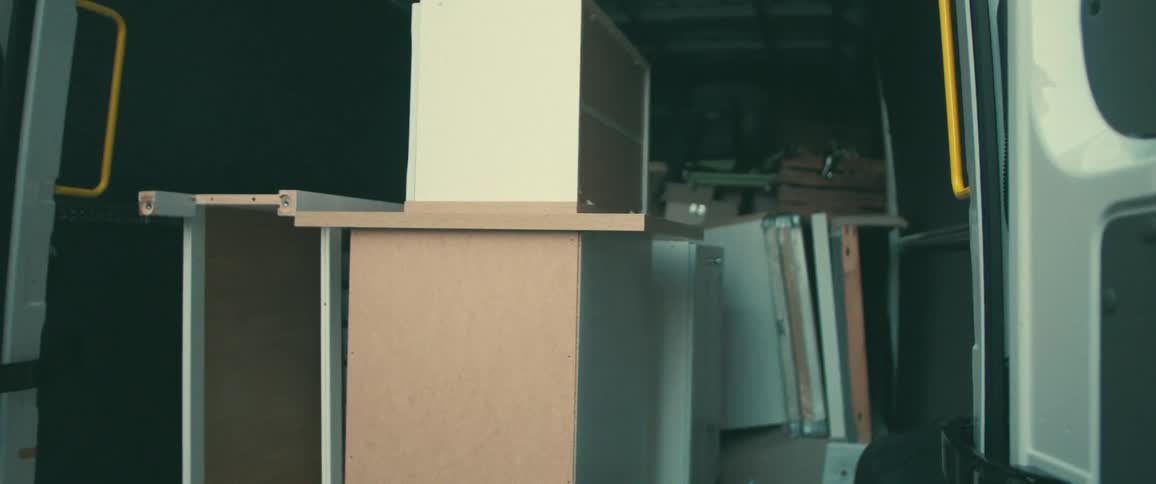 Disassembled kitchen cabinets and furniture pieces shake and slide in the back of a moving van during transport