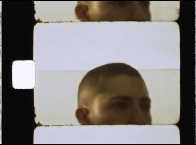 A static close-up Super 8mm film scan reveals the top of a person's head with a buzz cut