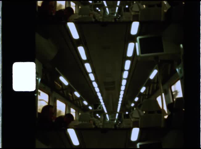 Vintage 8mm archival footage shows a perspective shot down the aisle of a passenger train car