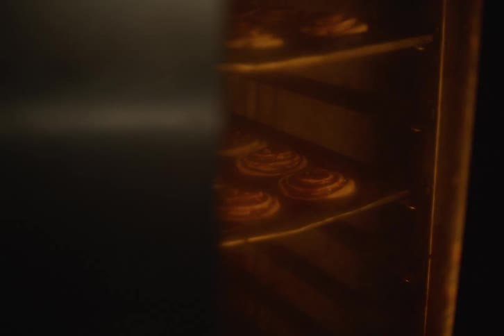 A warm and inviting close-up shot of delicious cinnamon buns baking and rotating inside a large industrial oven