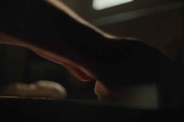 Moody close-up shot of hands kneading dough on a floured surface, preparing it for baking