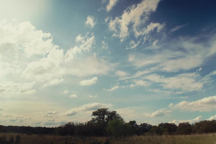 A peaceful time-lapse of beautiful clouds moving across a sunny sky over a rustic countryside landscape