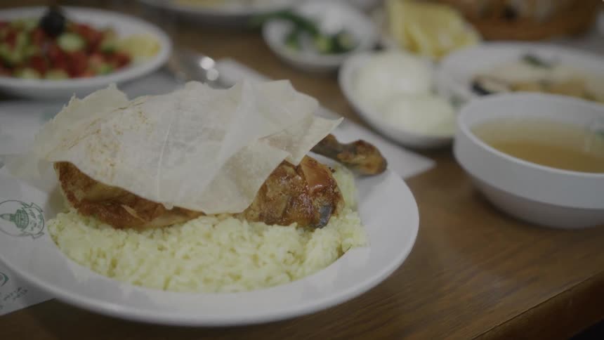A close-up shot of a delicious plate of roasted chicken and rice covered with flatbread, served at a restaurant