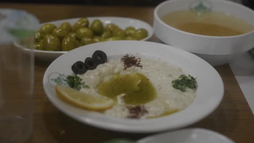 A close-up of a beautifully presented plate of hummus with olive oil and spices on a restaurant table