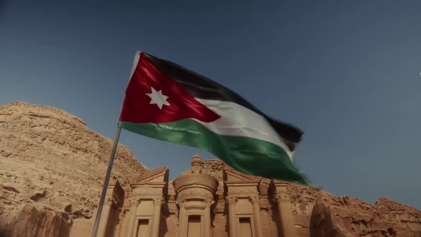 The Jordanian flag waves in the wind in front of the Ad-Deir Monastery, a monumental building carved into the rock in the ancient city of Petra, Jordan