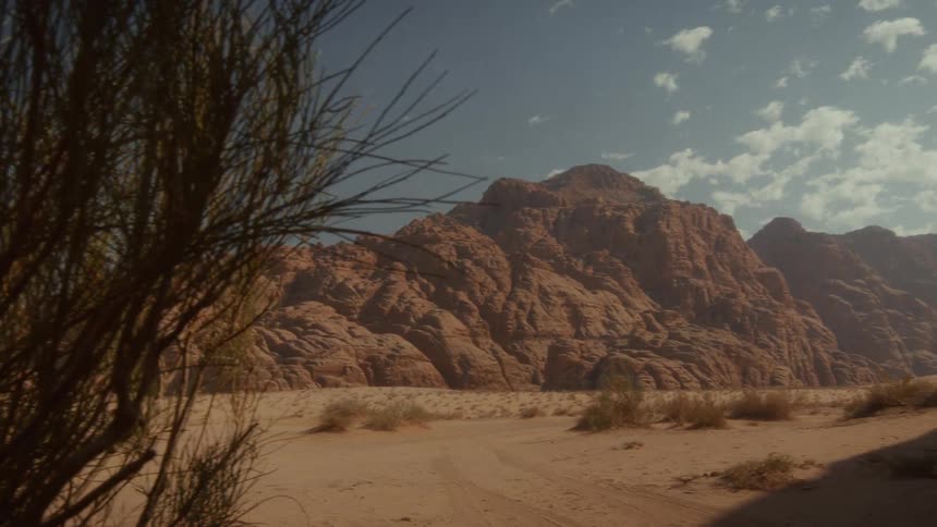 Slow pan reveals a breathtaking view of a majestic mountain range in a vast desert landscape