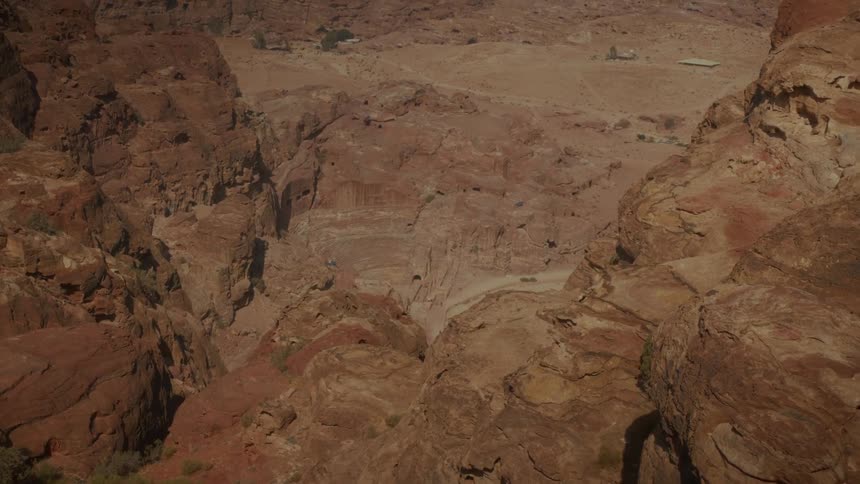 An expansive, high-angle view showcases the sun-drenched, red rock formations and canyons of ancient Petra