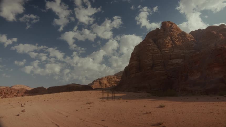 The iconic red rock mountains of the Wadi Rum desert in Jordan stand under a beautiful blue sky with white clouds
