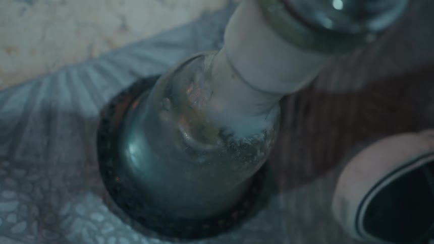A high-angle view of bubbling water and smoke in the glass vase of a hookah
