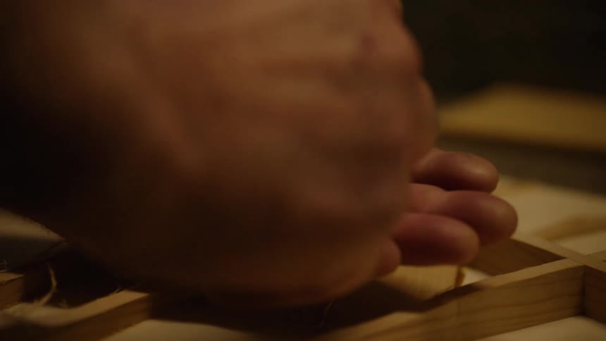 A slow motion, close-up shot shows a man's hand opening to reveal a small, white, abstract object in his palm