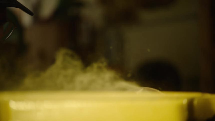 Slow motion close-up of a woodworker sanding a wooden piece on a belt sander, sending sawdust flying through the air
