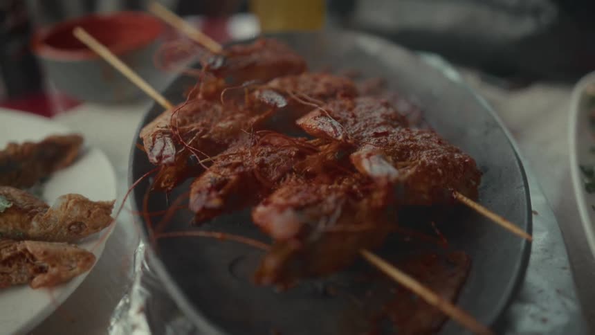 Steaming hot and spicy grilled shrimp skewers are served on a platter at the dinner table