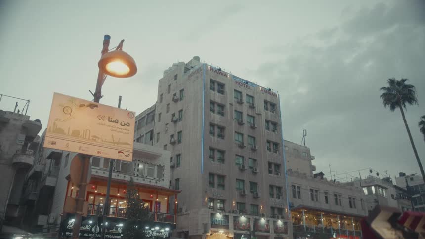 A low-angle establishing shot of the Hawa Hotel in Amman, Jordan under a moody, overcast sky at dusk