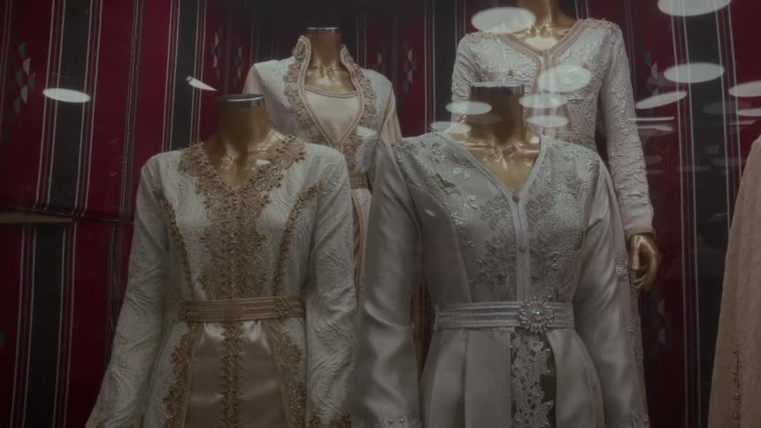 Elegant traditional Moroccan caftans are displayed on mannequins in a shop window
