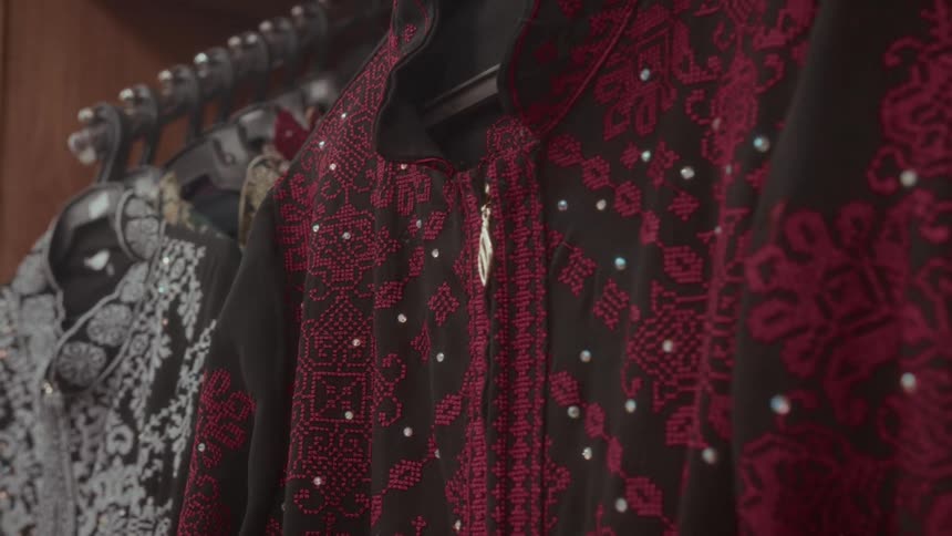 A close-up shot of a beautifully embroidered traditional black and red dress with sequins hanging in a shop