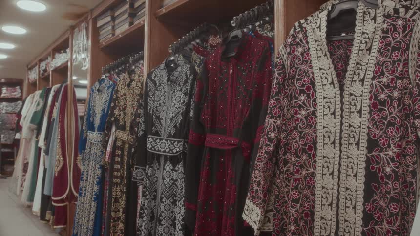 A collection of beautiful, embroidered traditional Arab dresses hang on display in a clothing boutique