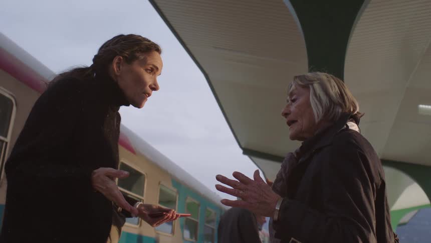 Slow motion low angle shot of two older women having an intense and emotional conversation on a train station platform