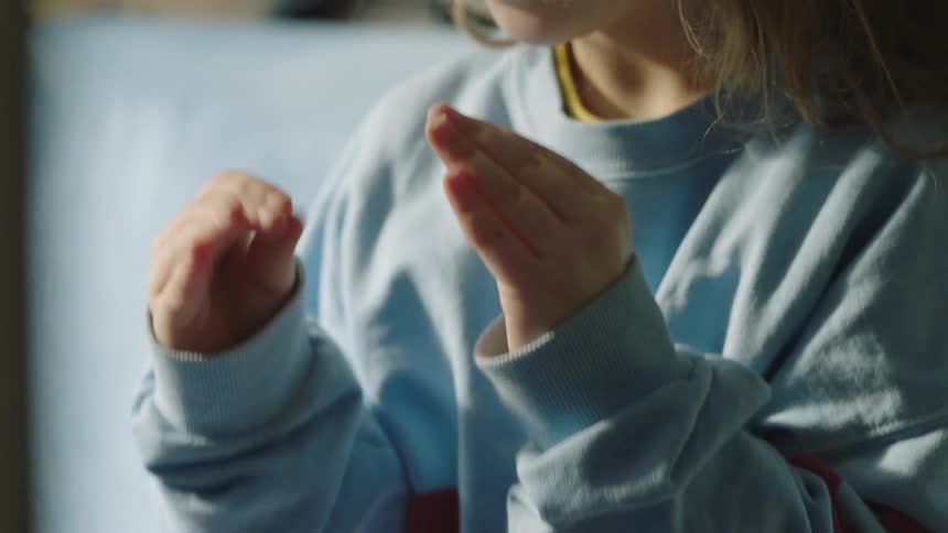 A close-up, slow-motion shot of a child's hands gesturing expressively in soft, natural light