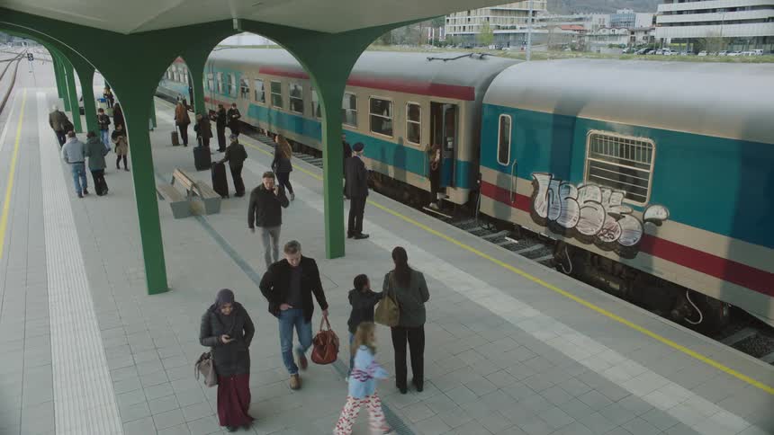 Slow motion high angle view of diverse travelers walking on a modern train station platform