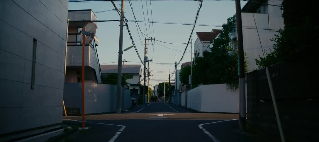 A still shot of an empty intersection in a quiet Japanese residential neighborhood during a peaceful sunrise