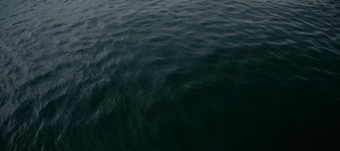A serene, moody top-down view of deep, dark ocean water gently rippling and flowing