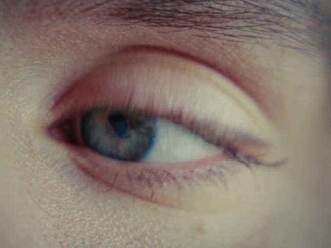 An extreme close-up shot of a restless blue eye darting around nervously
