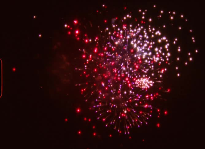 Vintage film captures a dreamy display of red, white, and purple fireworks exploding in the black night sky