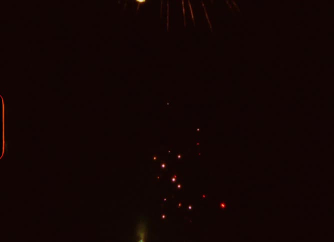 A vintage home movie captures a vibrant fireworks show exploding against the pitch-black night sky