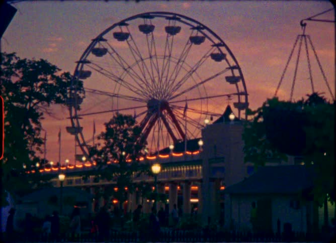 Nostalgic vintage footage shows a silhouetted Ferris wheel at an amusement park against a vibrant twilight sky