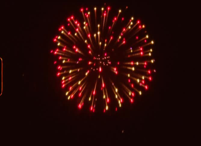 Colorful fireworks burst and sparkle against the dark night sky in this retro 8mm film clip