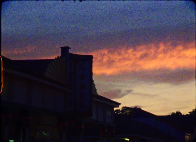 A vintage film style shot of an arcade silhouetted against a vibrant and colorful sunset sky