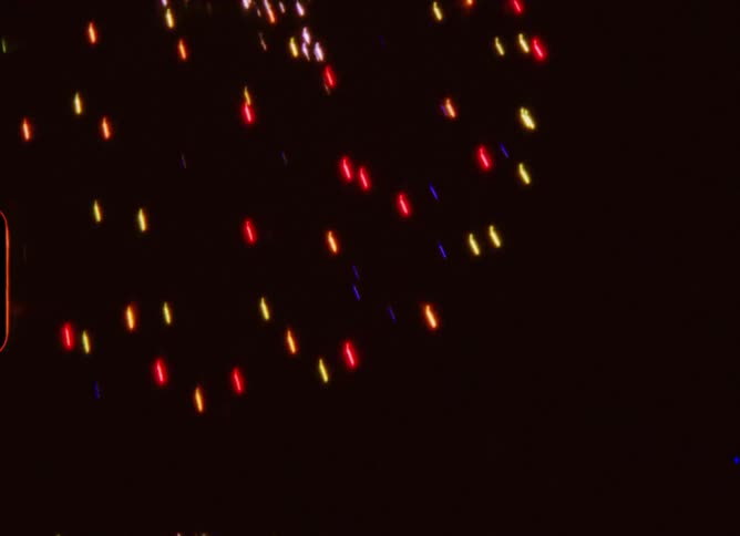 A nostalgic Super 8mm film captures an abstract light show and a variety of colorful fireworks exploding against the dark night sky