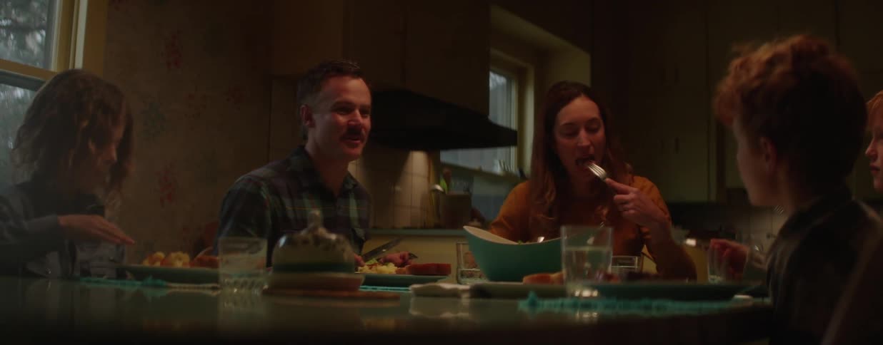 A family eats dinner together in their cozy, warmly lit kitchen