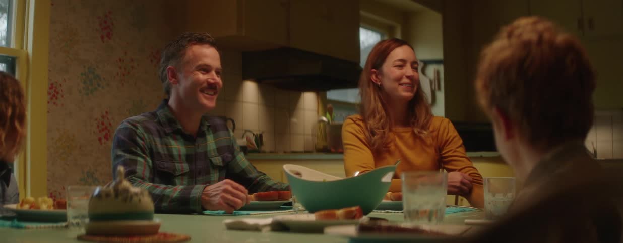 A joyful family shares a hearty laugh while sitting together at the dinner table in their cozy home