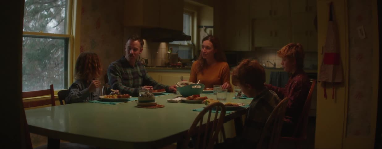 A family of five gathers around their dinner table for a quiet evening meal together at home