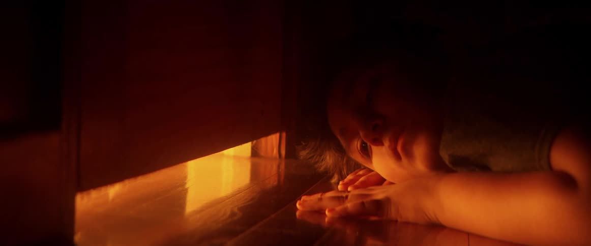 Cinemagraph of a scared child hiding in the dark, peeking under a door at a warm, flickering light