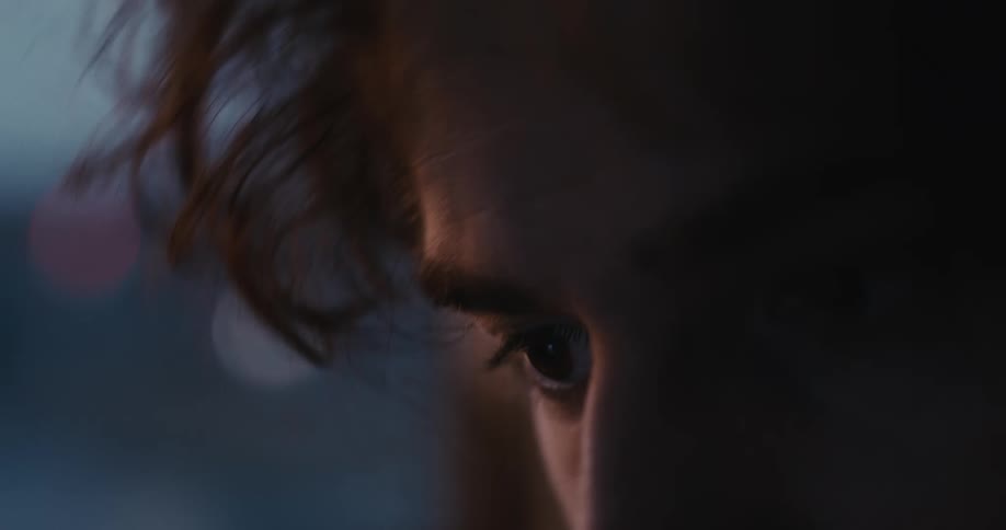A dramatic and moody extreme close-up of a person's eye looking down with intense focus in a dimly lit setting