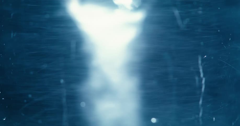 An abstract visual of a swirling vortex of white light and particles that forms and dissipates in a dark blue space