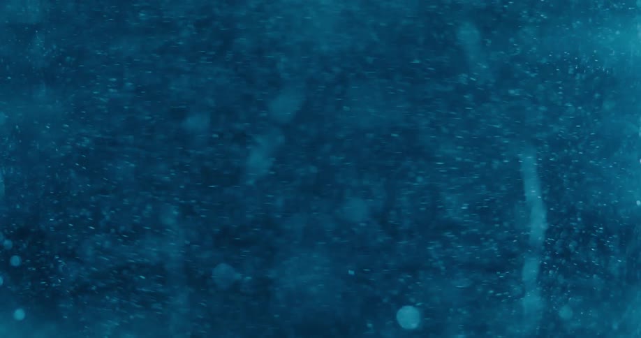 Mesmerizing out-of-focus particles swirl chaotically in a dark teal liquid background
