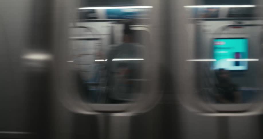 A New York City F train arrives at a dark subway station and speeds past the camera