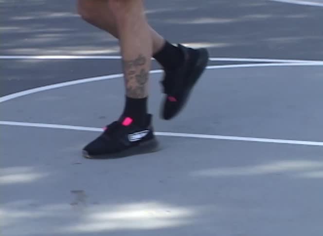 A close-up on the sneakers of a person doing a jump rope workout on an outdoor basketball court