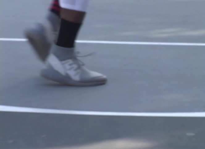Close-up of a man's feet shuffling and pivoting while practicing basketball on an outdoor court
