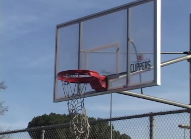 A basketball sinks through the net of an outdoor basketball hoop in slow motion