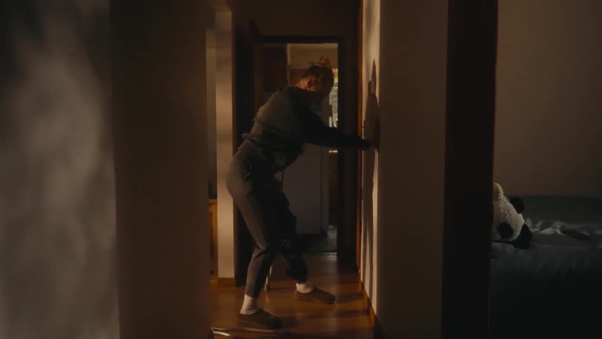 A distressed woman with crutches struggles and collapses in a dark hallway at home