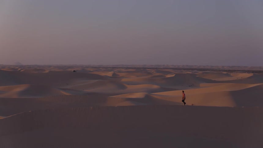 A man is hiking in the desert at dawn