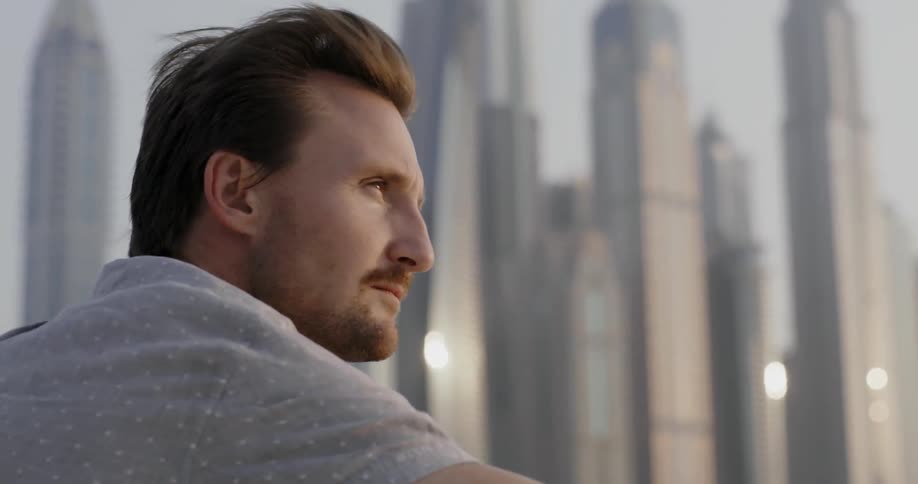A man sits on a windy day looking at a city