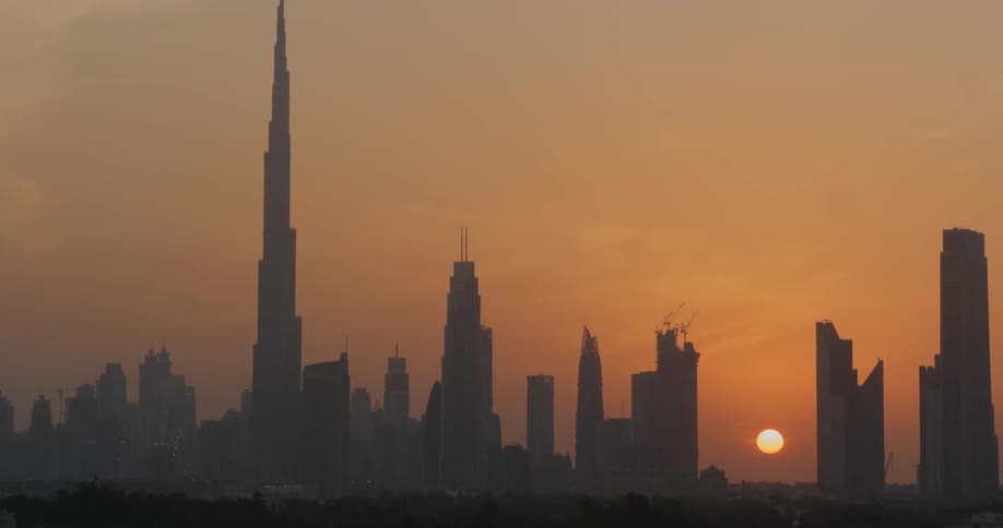 The sun is almost set behind these very tall buildings