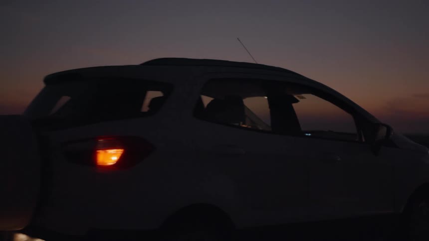 A man drives his suv in a desert landscape at dusk